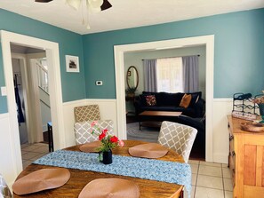 A dining area with a wooden table, patterned placemats, and a vase of flowers.