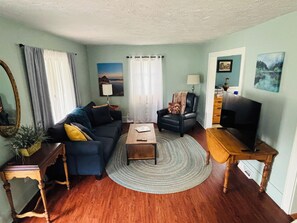 A living room with a sofa, armchair, coffee table, and television. - It's a Wonderful House! (Indiana)