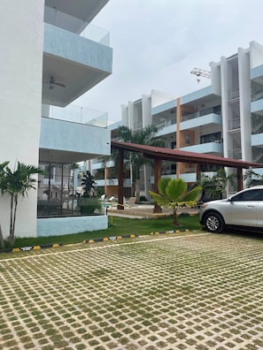 A modern building with multiple floors, outdoor seating, and a parking area. - Bayahibe Sunshine 2BR Pool Close to the Beach (San Rafael del Yuma)
