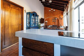 A kitchen with a wooden door, a blue cabinet, a dining table, and a window with curtains. - Spacious Home for 10 – 2 km from Peña de Bernal (Bernal)