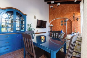 A dining area with a blue cabinet, a glass table, and a TV mounted on the wall. - Spacious Home for 10 – 2 km from Peña de Bernal (Bernal)