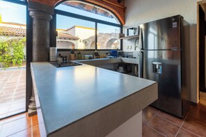 Eine moderne Küche mit einem Edelstahl-Kühlschrank, einem Einbauofen und einem großen Fenster mit Blick auf einen Innenhof.