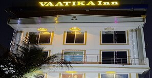 Een meerlaags gebouw met een bord waarop 'VAATIKA Inn' staat.