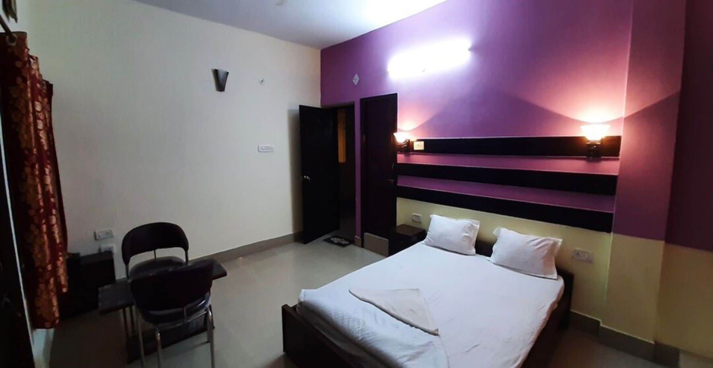 Una habitación de hotel con cama, una silla, un escritorio y una puerta.