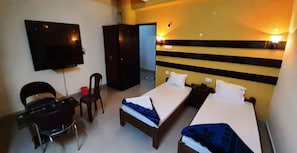 Een hotelkamer met een bed, een bureau, een stoel, een televisie en een kledingkast.