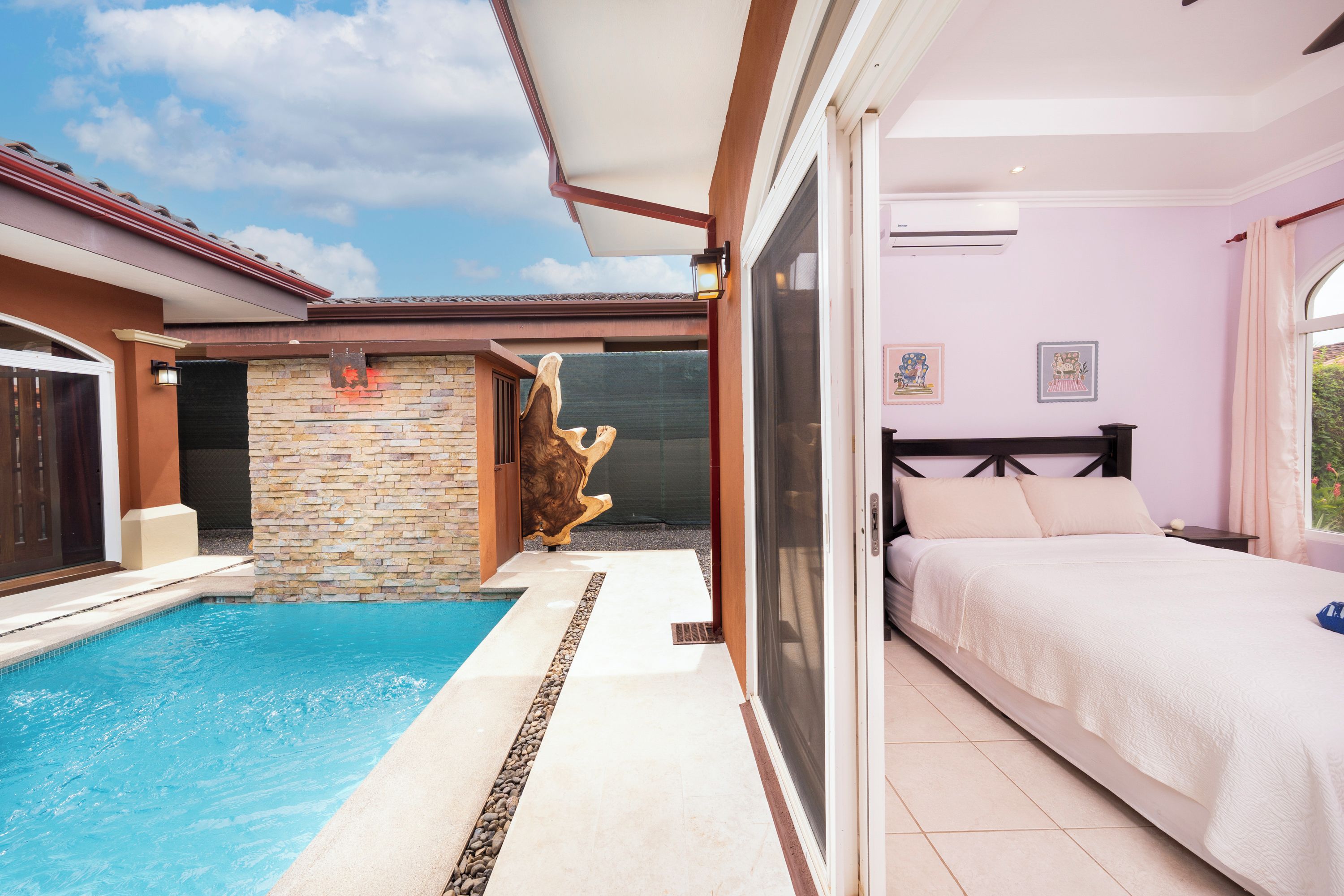 A bedroom with a bed, a window with curtains, and a view of a swimming pool.