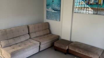 A modern living room with a sectional sofa, a small ottoman, and two wall-mounted artworks.