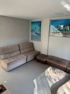 A modern living room with a sectional sofa, a small ottoman, and two wall-mounted artworks. - LaFayette Residence (São Paulo)