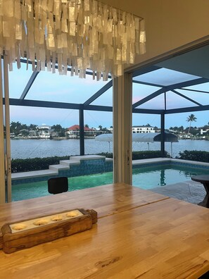 Ein Holztisch mit Kerzenhalter, Blick auf einen Swimmingpool und eine Glastrennwand.
