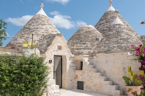 A building with multiple stone cone-shaped roofs, a door, and a small window. - Luxury Trulli Zaccano Estate with Private Pool, Cisternino (Puglia)