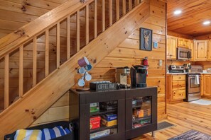 A wooden staircase leading to a kitchen area with a coffee bar, cabinets, and a microwave. - Hot Tub • Game Room • 3 King Beds • Pet Friendly (Ellijay)