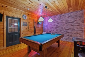 A pool table in a room with wooden walls and a brick accent wall. - Hot Tub • Game Room • 3 King Beds • Pet Friendly (Ellijay)