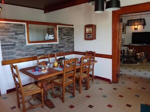 A dining area with a wooden table and chairs, a clock on the wall, and a patterned floor.