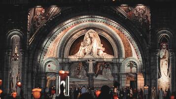 Een kathedraalinterieur met een groot centraal portaal, beelden en mensen met kaarsen.