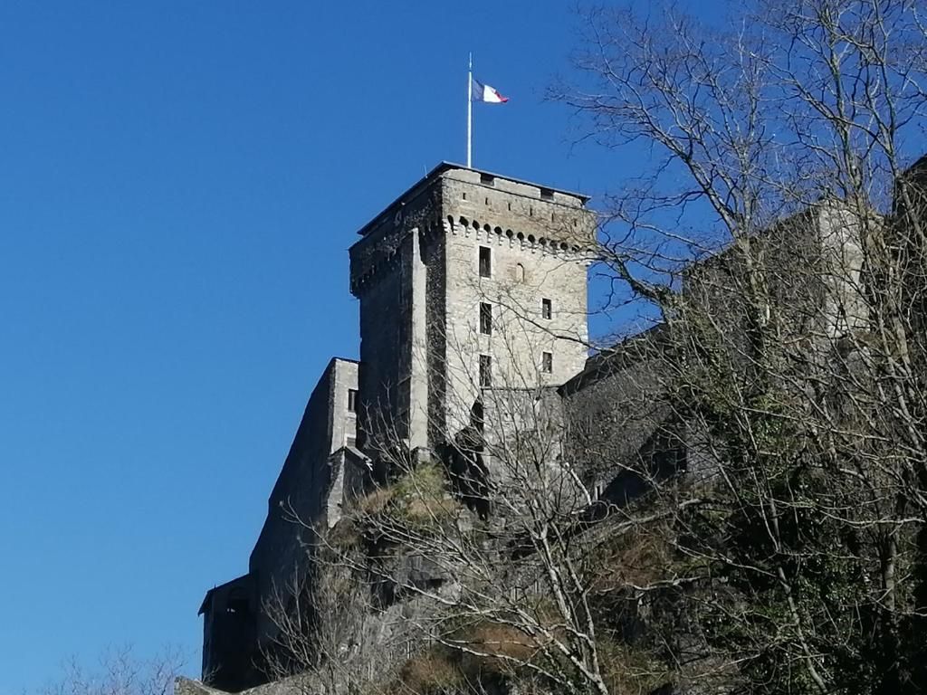 Ein historischer SteinTurm mit einer Flagge auf der Spitze, umgeben von Bäumen.