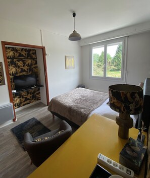 A bedroom with a bed, a desk, a chair, a lamp, a TV, and a window. - La maison de Barlest  (Barlest)