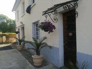 A building with a white and blue exterior, a black door, and hanging flower baskets.
