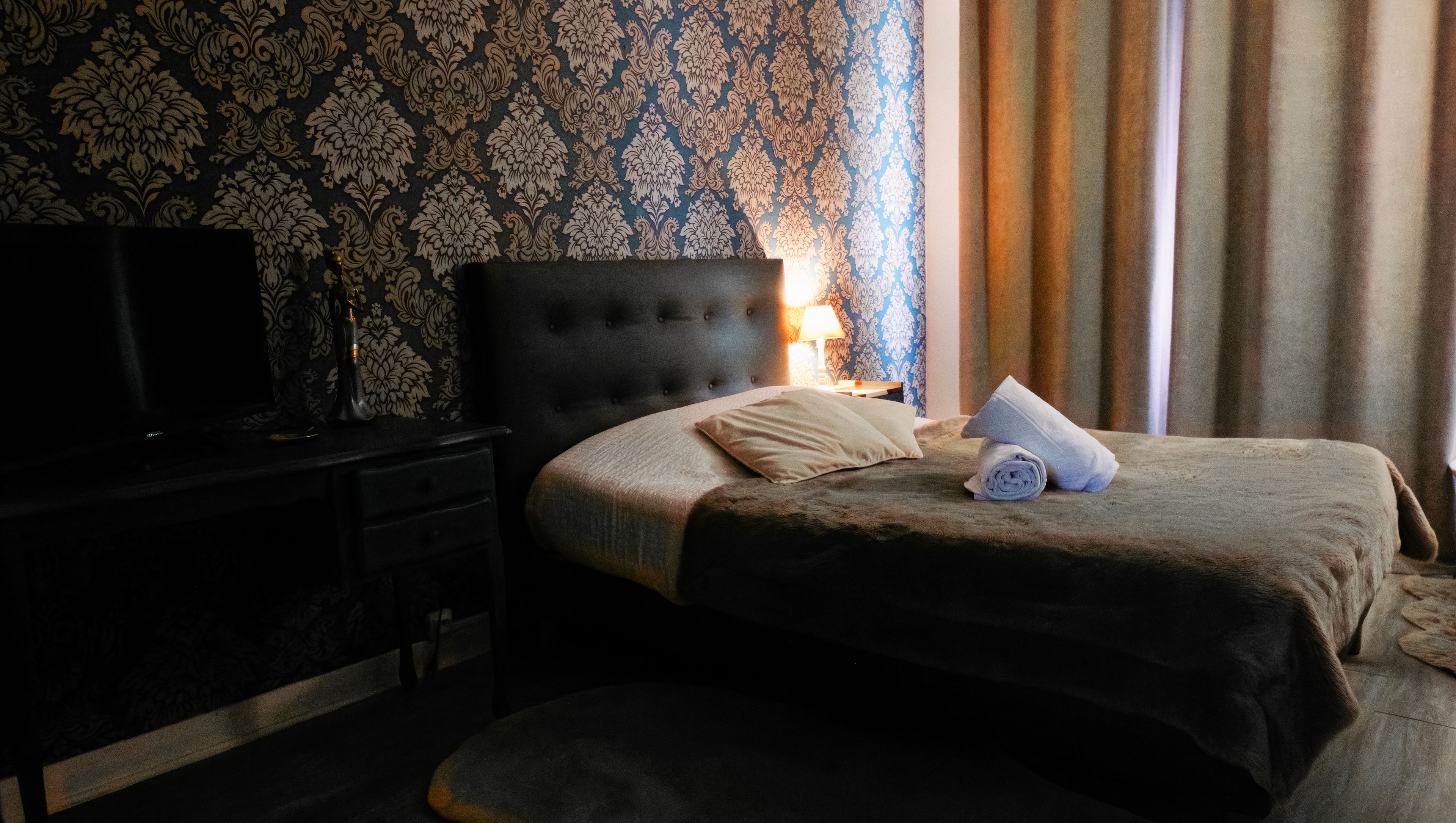 Ein Hotelzimmer mit einem Bett, einem Fernseher, einem Nachttisch und einer Lampe.