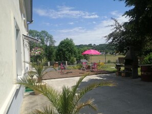 An outdoor patio area with a barbecue grill, a pink umbrella, and outdoor seating.