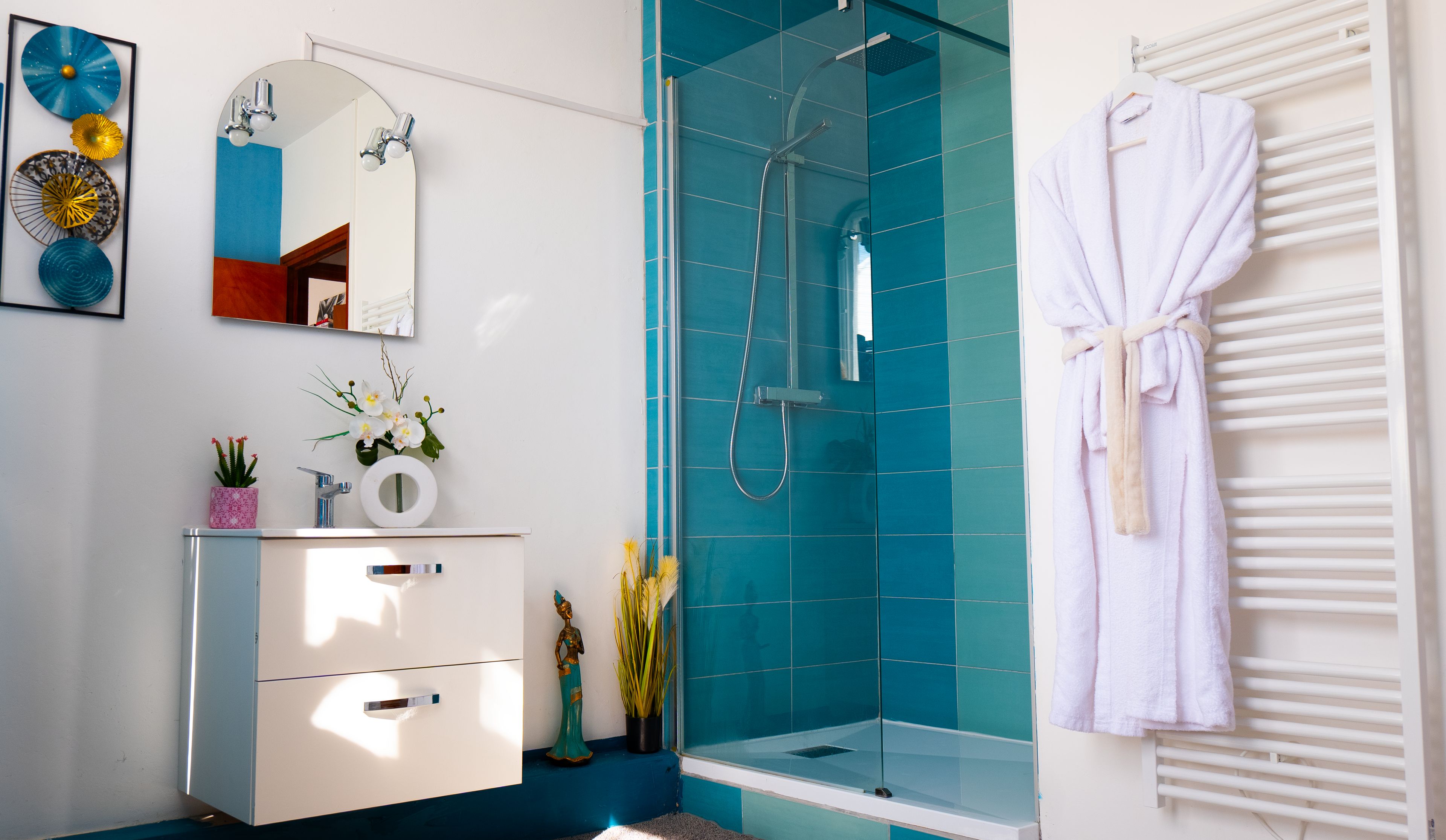 A modern bathroom with a glass shower enclosure, a white vanity, and a white bathrobe hanging on a radiator.