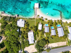 Vista aérea de un resort con varias construcciones, una playa y aguas turquesas cristalinas.
