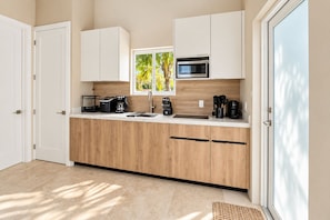Una cocina moderna con armarios de madera, microondas integrado y cafetera.