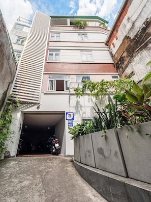 A narrow alleyway leading to a building entrance with a sign indicating a parking area. - YOUR HOME - Garden Studio 35m² (Ho Chi Minh City)
