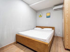 Ein Schlafzimmer mit einem hölzernen Bett, weißer Bettwäsche und zwei Wand-Klimaanlagen.