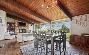 A spacious living area with a dining table, chairs, a fireplace, and a television. - Beachside Dream · Spacious 4-bedroom home in Stevensville (Stevensville)