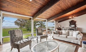 A spacious living room with a large window, a wooden ceiling, and a cozy seating area. - Beachside Dream · Spacious 4-bedroom home in Stevensville (Stevensville)