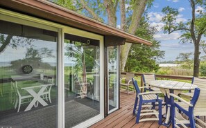 Eine Terrasse mit Gartenmöbeln und einer Glastür, die zu einem überdachten Bereich führt.