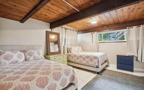 Een slaapkamer met twee bedden, een nachtkastje, een dressoir, een spiegel en een raam met gordijnen.