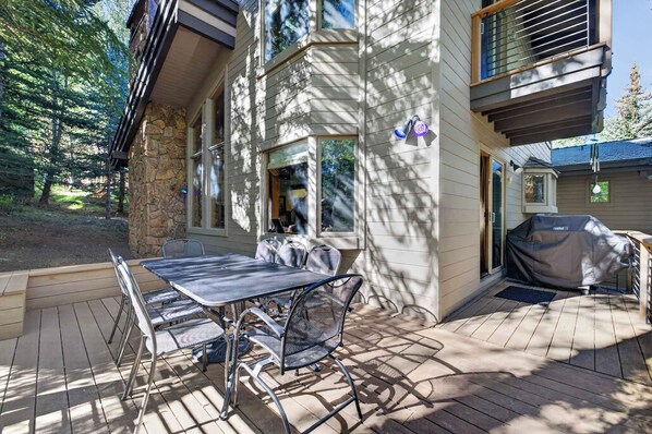 An outdoor patio with a table and chairs, a stone wall, and a covered grill area. - Spring Hill Hideaway Fireplace (Vail)