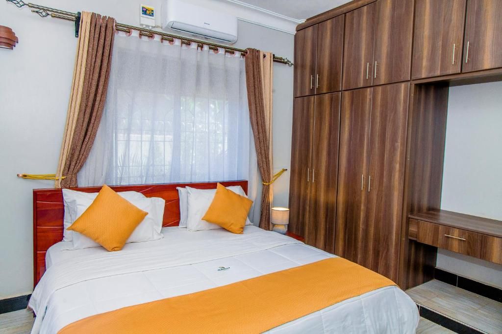 Habitació d'hotel amb llit, cortines, un armari i una taula de nit.