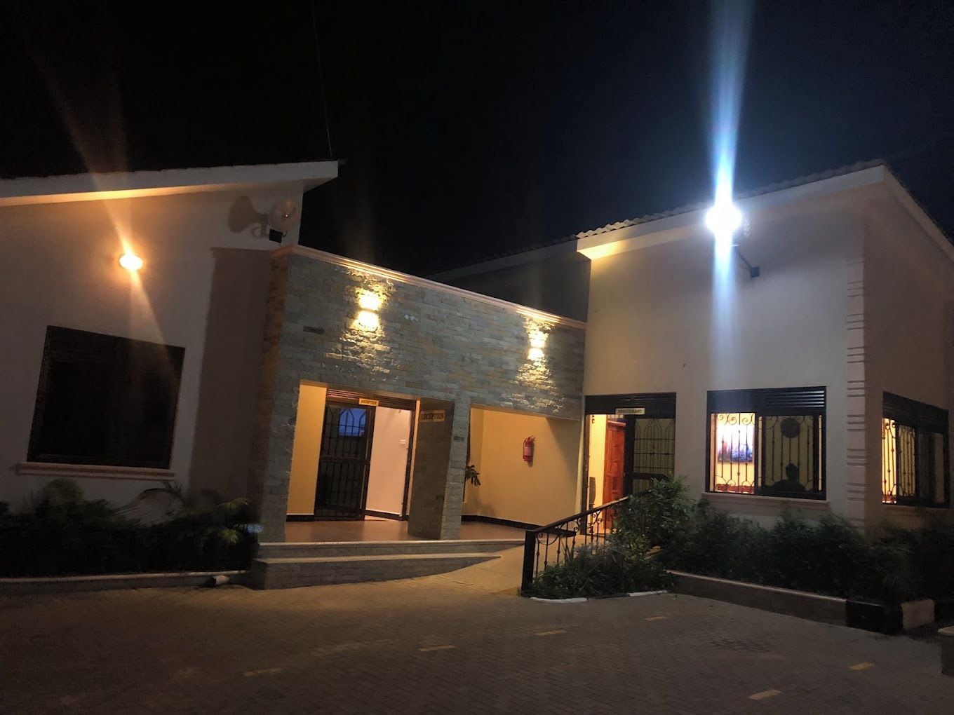 Un edificio con entrada central y una escalera que lleva a ella, y un exterior bien iluminado.