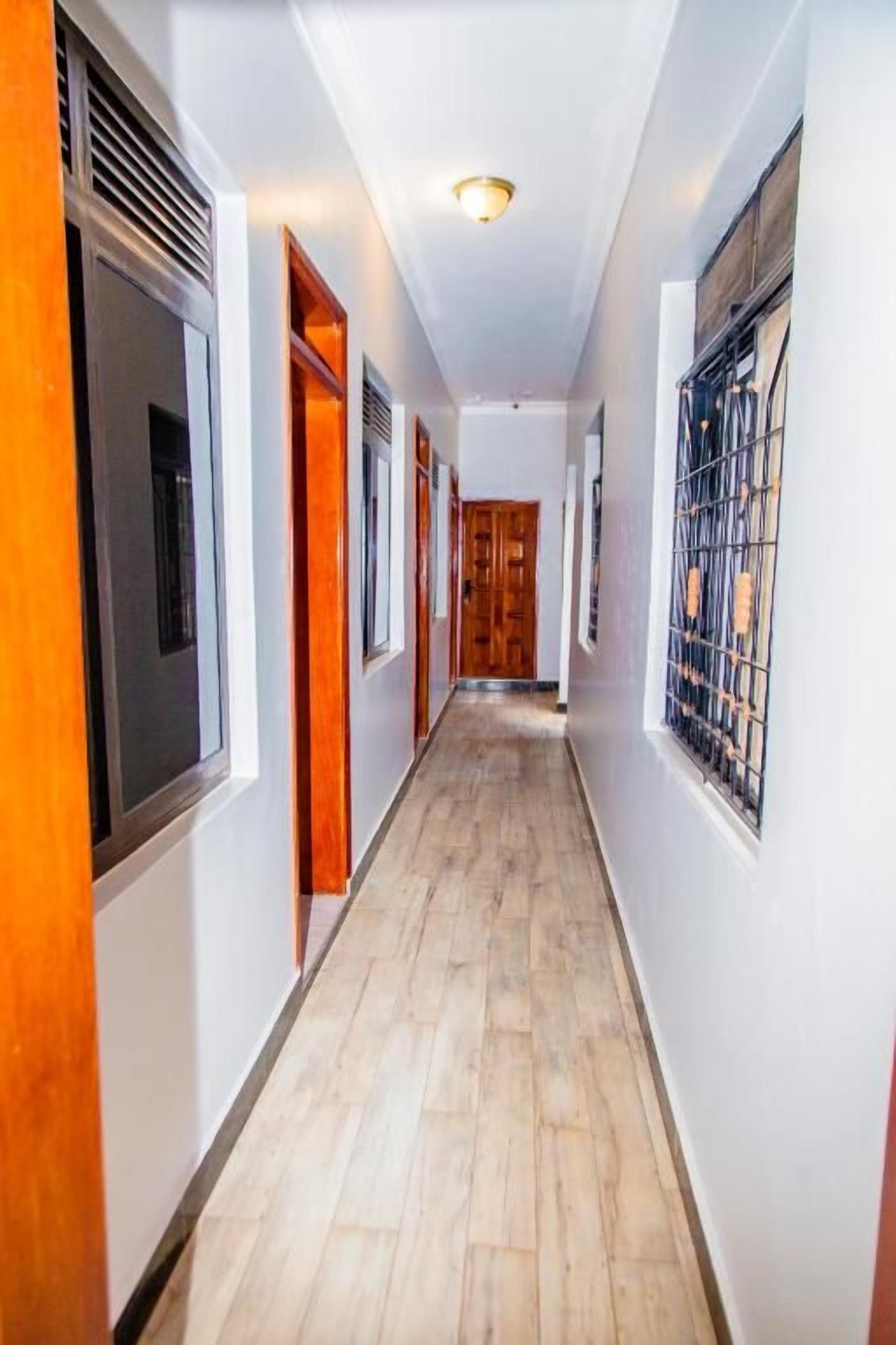 Un pasillo con piso de madera, paredes blancas y puertas que dan a habitaciones.