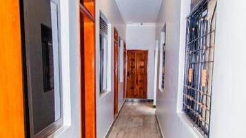 Un pasillo con piso de madera, paredes blancas y puertas que dan a habitaciones.