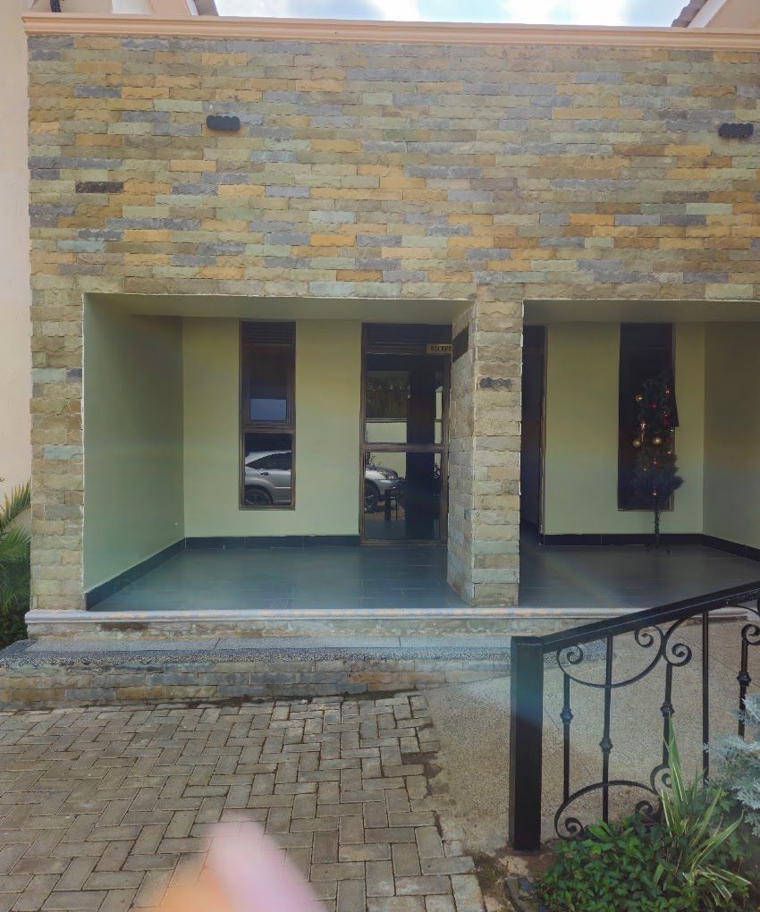 Un edificio con fachada de piedra, un acceso cubierto y una escalera que lleva a un balcón.