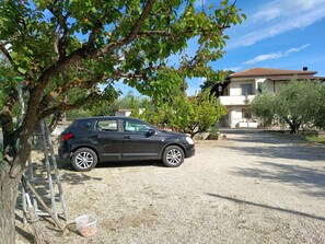 A black car parked on a gravel driveway with a ladder and a broom leaning against a tree. - Mediterranean Coast: airport, train stations, beach, museums 10 minutes away, skiing 50 minutes away (Abruzzo)