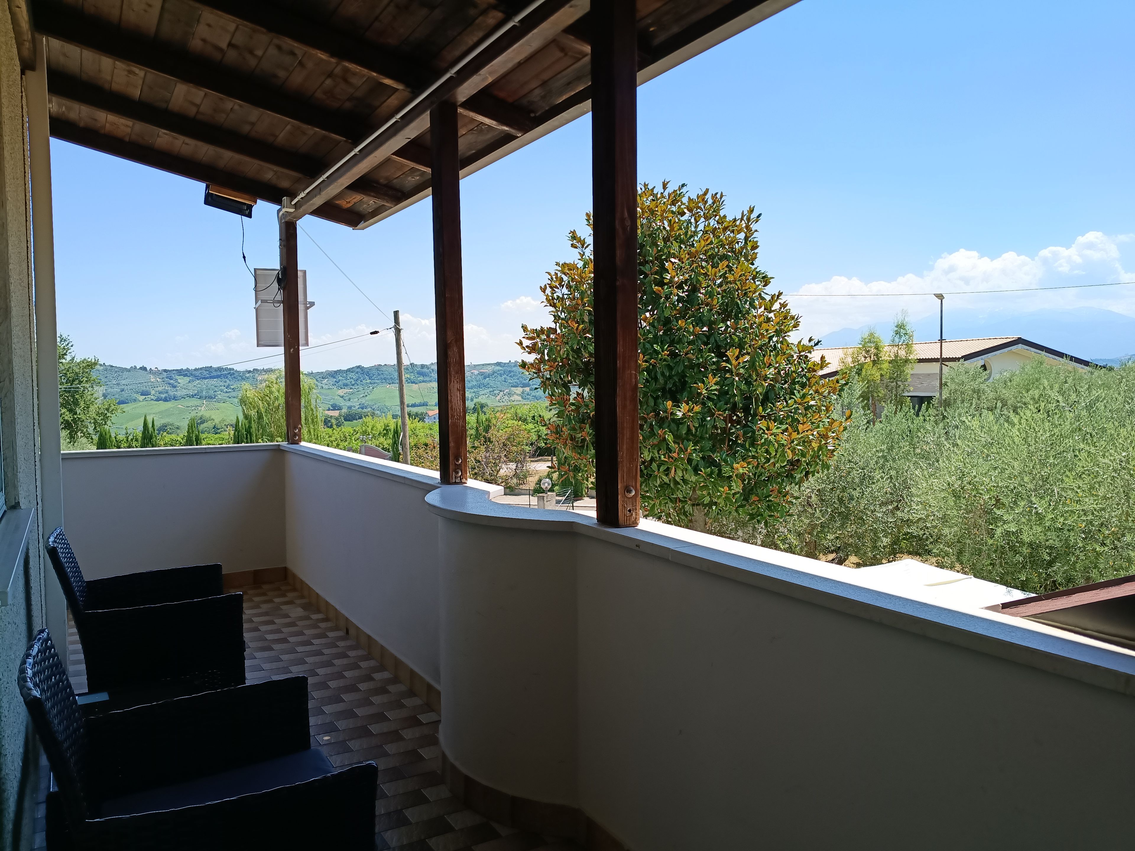 Un balcón con vistas a un paisaje verde y un edificio a lo lejos.