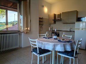 A dining area with a table set for two, chairs, a bottle of wine, and a view of the outdoors. - Mediterranean Coast: airport, train stations, beach, museums 10 minutes away, skiing 50 minutes away (Abruzzo)