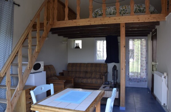 A cozy living area with a wooden staircase, a sofa, a table, and a radiator.