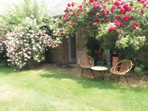 En have med blomstrende planter og to fletstole.