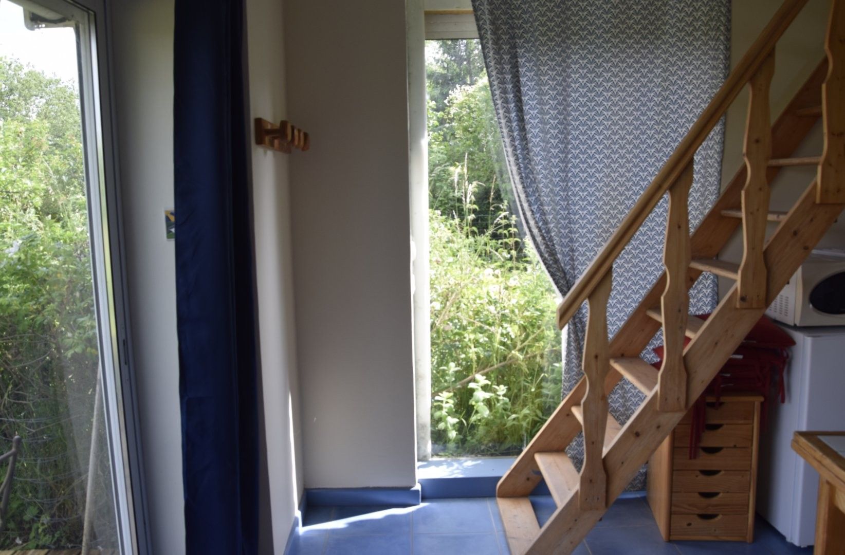 A wooden staircase leading to a balcony with a view of greenery outside.
