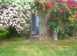 En have med blomstrende planter, en stenvæg og en dør.