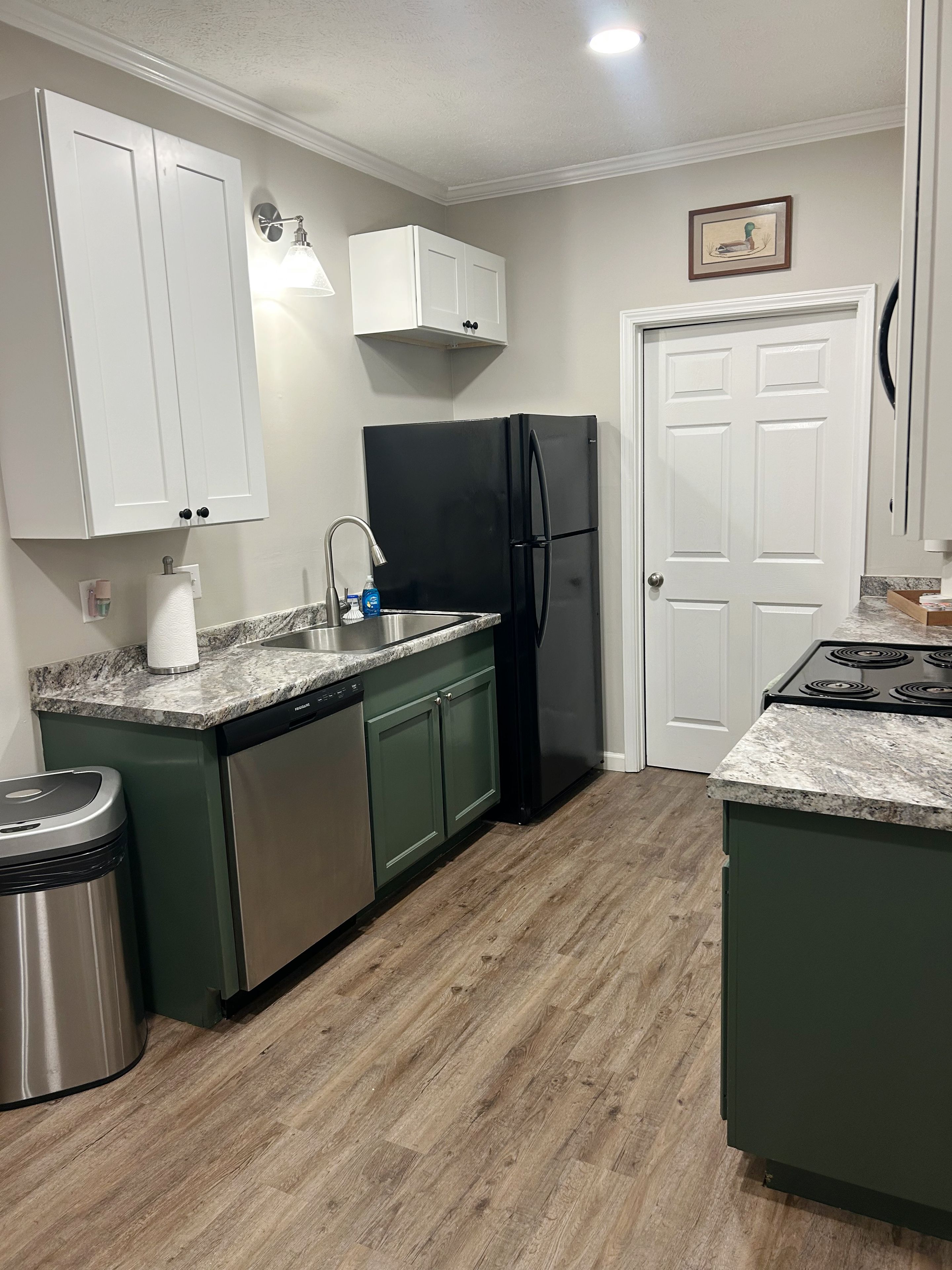 A kitchen with a sink, a black refrigerator, and a stove.