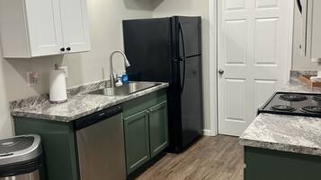A kitchen with a sink, a black refrigerator, and a stove.