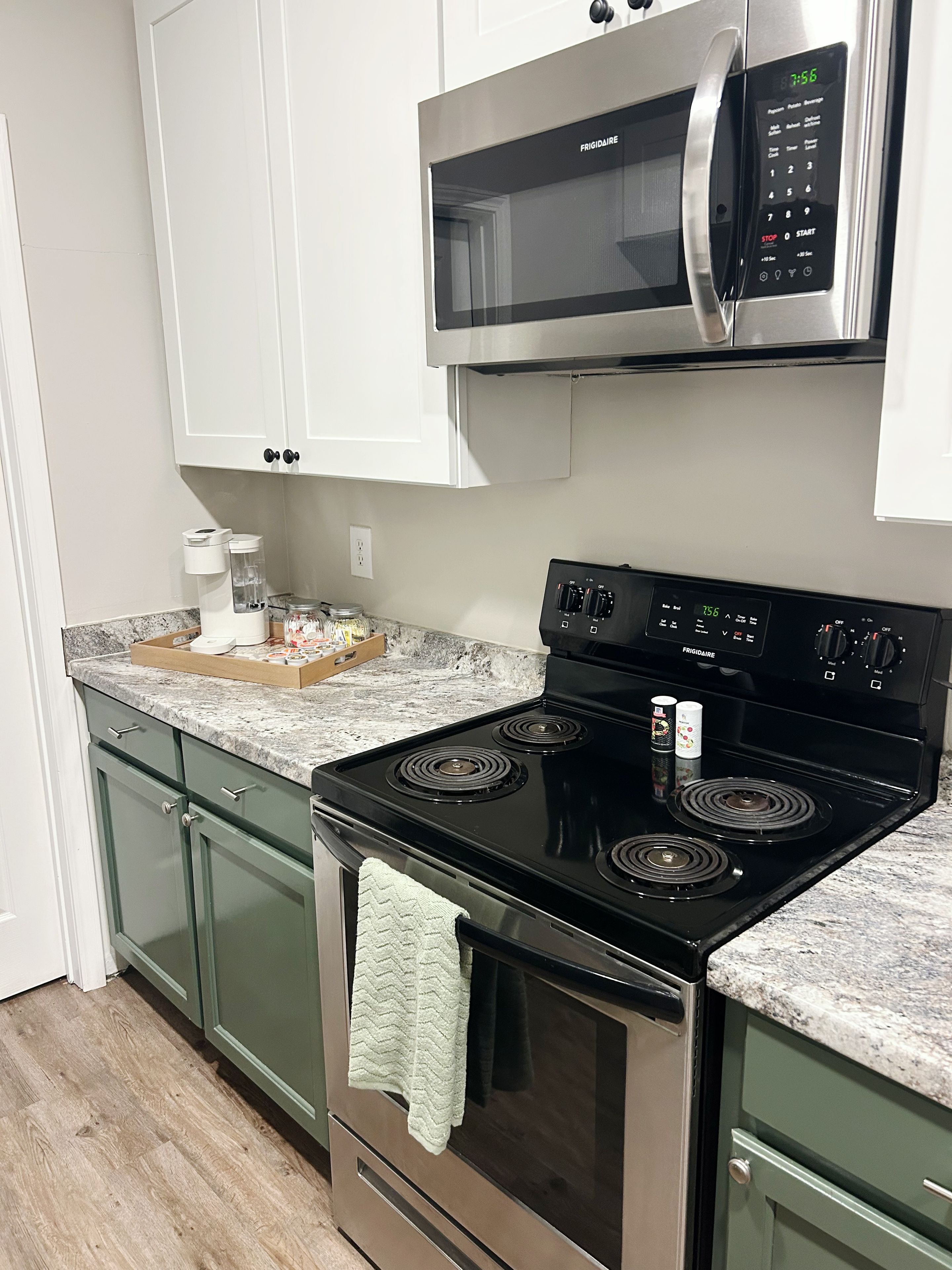 A kitchen with a black stove, a microwave, and a coffee maker on the counter.