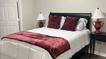A bedroom with a bed, two bedside tables, a door, and a ceiling fan.