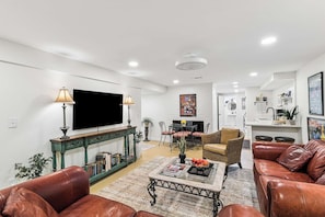 A modern living room with a flat-screen TV, leather sofas, a coffee table, and a dining area with chairs and a table. - Cozy Retreat Apartment | Near Downtown Nash (Nashville)